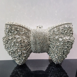 Detailed close-up of a silver bow clutch bag covered in shimmering rhinestones and crystals