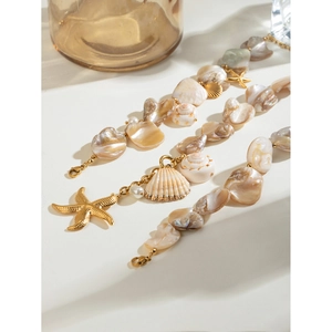 Macro detail of 18k gold chain featuring natural seashells and a starfish charm pendant