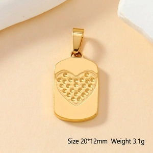Vue macro d'un pendentif coeur en acier doré avec texture pointillée et taille de 20x12mm