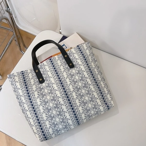 Detailed shot of floral cotton tote with premium black leather handles and gold rivets