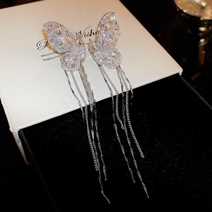 Macro shot of silver butterfly tassel earrings with sparkling cubic zirconia on box
