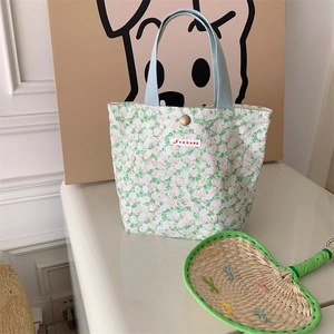 Dettaglio macro della borsa da pranzo in tela floreale con manici blu e bottone a pressione