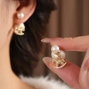 Elegant gold earrings with dual white pearls and a sparkling zircon rocking horse pendant