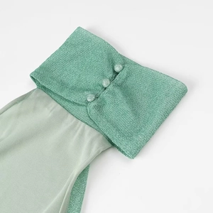Detail of green sequin knit cuff with three buttons and sheer chiffon sleeve fabric