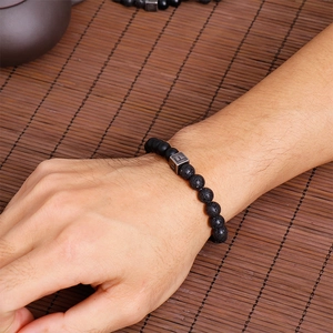 Detailed close-up of men's lava stone beaded bracelet with letter F metal accent