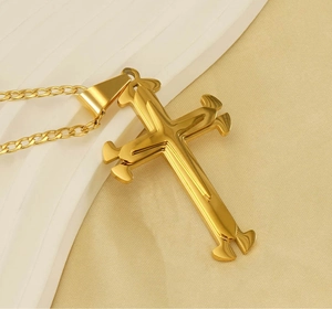 Macro detail of multi-layered 18k gold-plated stainless steel cross pendant on Cuban chain