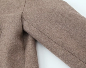 Detailed close-up showing the brown wool blend fabric and neat shoulder seams of the coat