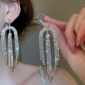 Gros plan de boucles d'oreilles à pompons argentées avec strass et structure en U