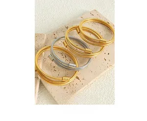 Close-up of multilayer gold and silver snake bone chain bracelets on a stone base