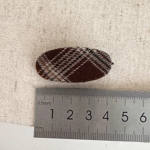 Macro view showing a 4.5cm brown checkered fabric hair clip measured with a ruler
