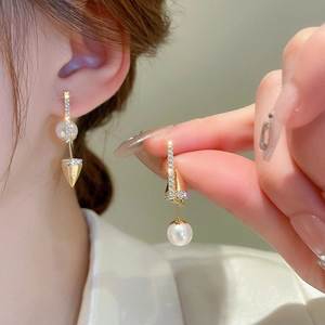 Detail of 18K gold plated drop earrings with white pearl and sparkling geometric charm