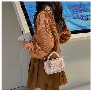 Detailed view of pink tweed kids handbag featuring a pearl handle and daisy embroidery