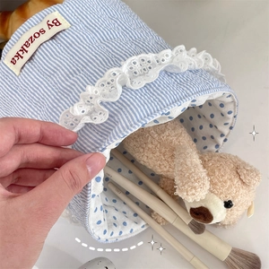 Close-up of heart quilted storage basket with lace trim holding brushes and plush bear