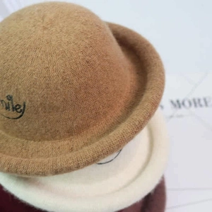 Detail showing stacked wool felt hats with cute smile embroidery and rolled brim for kids