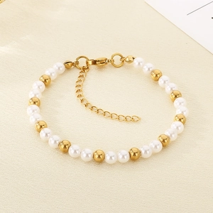 Close-up of white pearls and gold beads woven bracelet with lobster clasp and chain