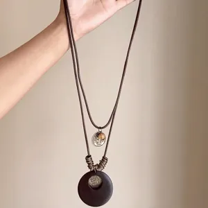 Bohemian long tassel pendant necklace featuring a vintage resin disc and metal accents