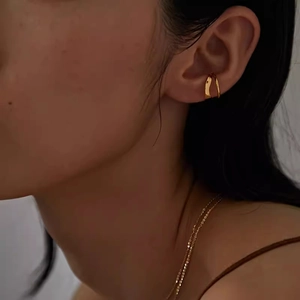 Minimalist double-layered gold ear cuff for women shown on model in dim light