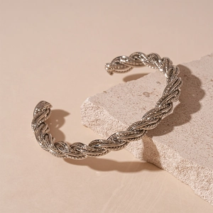 Detailed macro shot of silver twisted rope cuff bracelet on a minimalist stone display