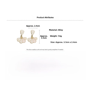 Detailed view of cream enamel flower earrings with gold edges and silver needles