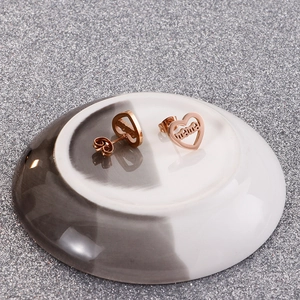 Detail shot of rose gold heart earrings featuring 'mama' engraving on ceramic plate