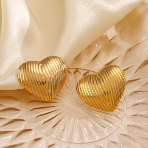 Elegant gold heart earrings with vertical textured stripes on a decorative glass tray