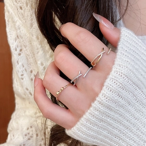 Close-up of elegant gold bow ring and silver zircon band layered on a finger