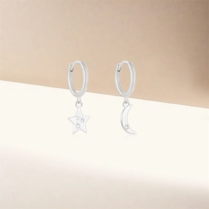 Detail of asymmetric S925 silver earrings with sparkling star and moon dangles