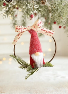 Detail of red Christmas gnome felt ornament hanging on tree with Merry Christmas ribbon