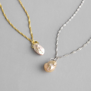 Baroque pearl necklaces with gold and silver water wave chains on a grey surface