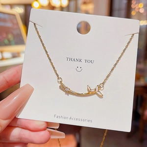 Detail of a gold floral pendant necklace with zircon stones on a Thank You display card