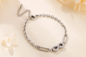 Detail of silver infinity link chain bracelet with adjustable clasp on beige background