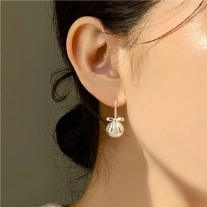 Close-up of 925 silver bow-knot pearl drop earring worn on a female model ear