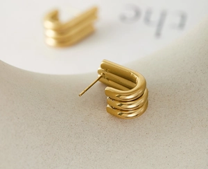 Detailed macro view of triple-layered U-shaped gold earrings in a matte finish