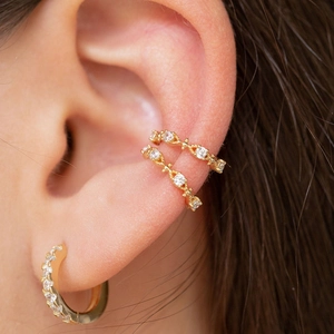 Macro shot of gold-plated ear cuffs and hoop earring set with sparkling white zircon stones