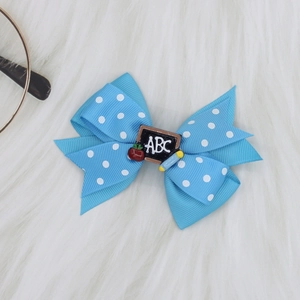 Detail of blue polka dot ribbon hair bow with ABC blackboard and apple school theme