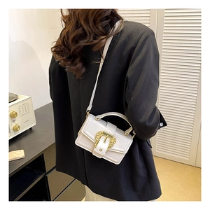 Close-up of white leather crossbody bag featuring a vintage gold buckle and top handle