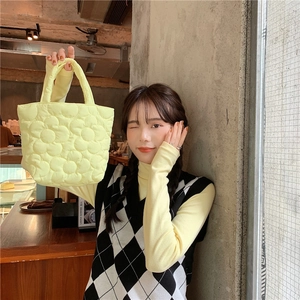 Detail of yellow quilted tote bag with floral pattern shown in a bright cafe setting