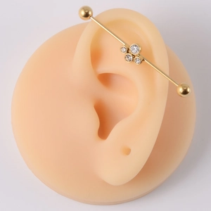Detailed view of a golden industrial barbell piercing with sparkling crystal flower gems