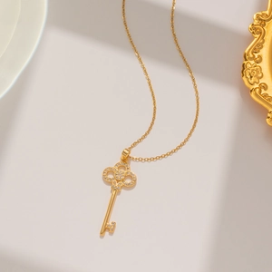 Macro shot of 18k gold plated key pendant with sparkling zircons on titanium necklace
