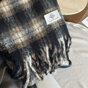 Black and beige plaid winter scarf with fringe detail and a woven logo label