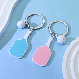 Blue and pink pickleball racket keychains with white ball charms on a stylish background