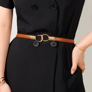 Detail of adjustable brown leather skinny belt with golden double ring buckle on black dress