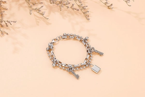 Detail of silver double-layer beaded chain bracelet featuring padlock and key charms