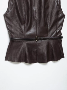 Détail du haut en cuir marron foncé avec une fine ceinture noire bouclée et texture