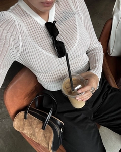 Detail of white ribbed knit long sleeve top paired with high waist trousers and sunglasses