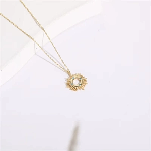 14K gold plated sunburst pendant necklace featuring turquoise zircons on a white platform