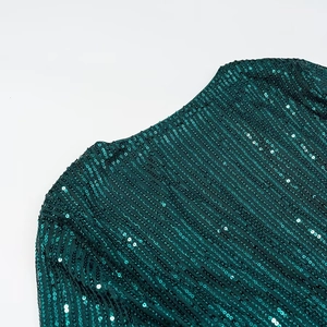 Close-up of deep green sequins and fine mesh fabric detail on the elegant V-neck dress