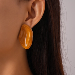 Close-up of model wearing an irregular amber resin geometric earring with a silver stud