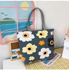 Detail of grey canvas tote bag featuring large colorful flower prints in a cozy setting
