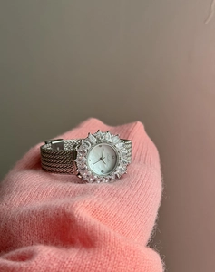 Dettaglio di orologio da donna elegante con ghiera in diamanti su morbido tessuto rosa